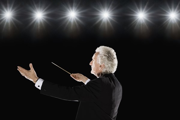 Man in tuxedo conducting under lights. Date : 2008