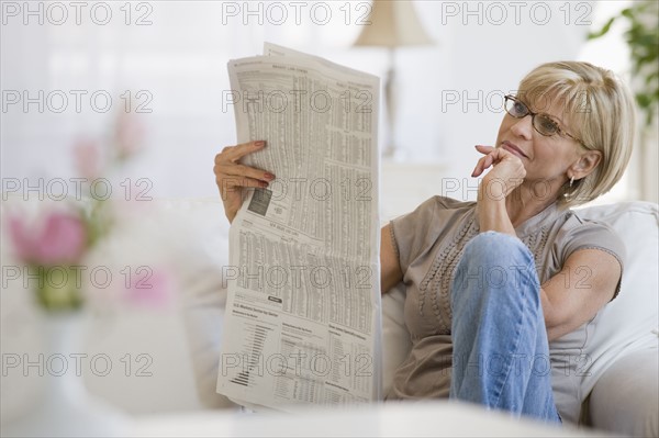 Woman reading newspaper in livingroom.