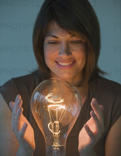 Woman holding hands around large light bulb.