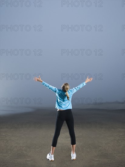 Woman with arms outstretched on foggy beach. Date : 2008