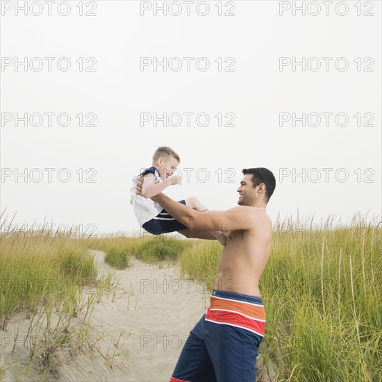 Father lifting son on beach. Date : 2008