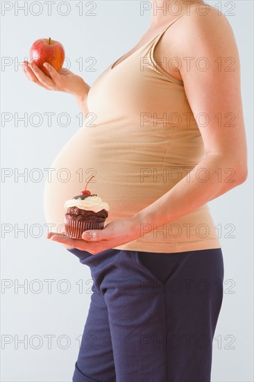 Pregnant woman holding healthy and unhealthy snacks. Photographe : Jennifer L. Boggs