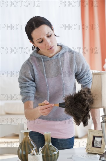 Woman dusting lamp.