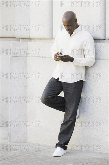 Man text messaging outside office building. Photographe : PT Images