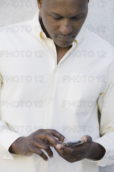 Man text messaging outside office building. Photographe : PT Images