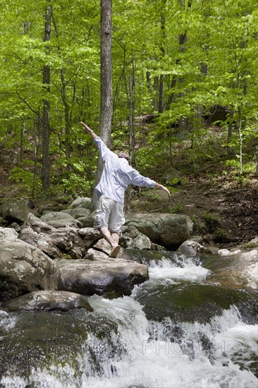 A man at a stream in the woods