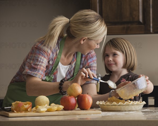 Mother and daughter baking apple pie. Photographer: Mike Kemp