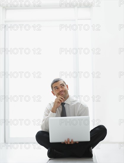 Businessman holding laptop. Photographe : momentimages