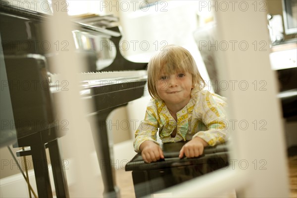 Young girl lying on piano bench. Photo : Tim Pannell