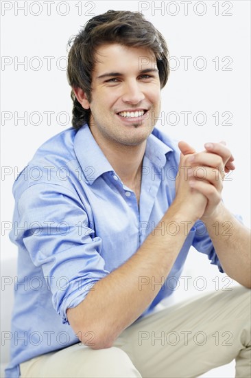 Handsome man sitting with hands clasped. Photo. momentimages