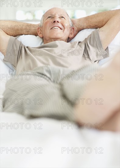 Relaxed senior man lying on bed. Photo : momentimages