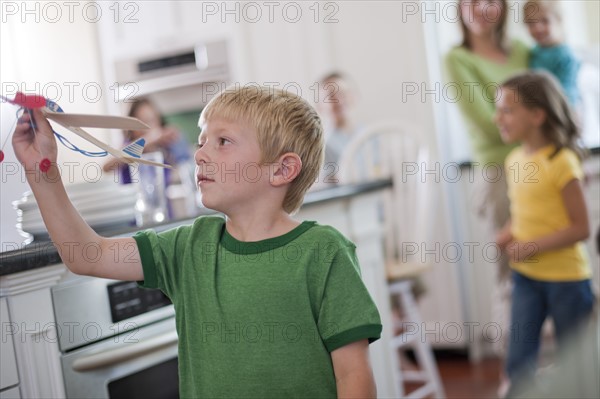 Young boy playing with toy airplane in kitchen. Photo : Tim Pannell