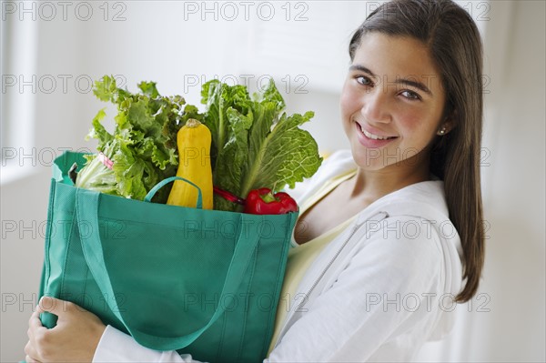 Portrait of girl (12-13) holding groceries .