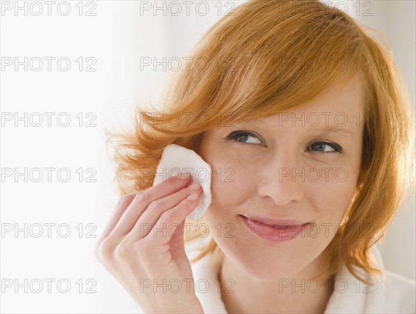 Young woman cleaning face with cotton pad. Photo : Jamie Grill
