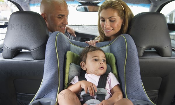 Young family with small girl (12-18 months) sitting in car.