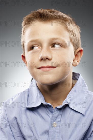 Portrait of boy (8-9) wearing shirt and looking away, studio shot. Photo : FBP