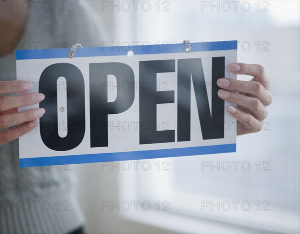 USA, New Jersey, Jersey City, Close-up view of woman holding open sign. Photo : Jamie Grill Photography