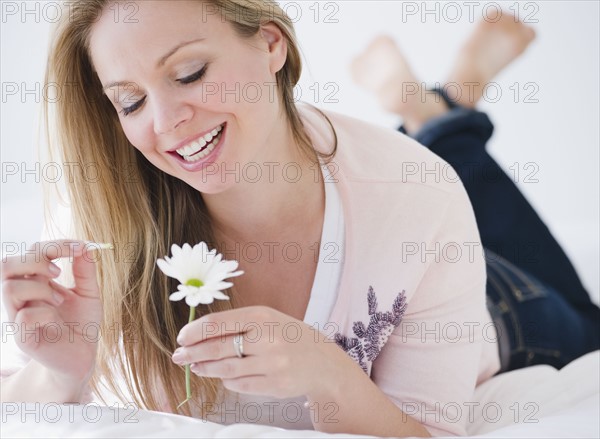 USA, New Jersey, Jersey City, Young attractive woman pulling petails out of flower head. Photo : Jamie Grill Photography