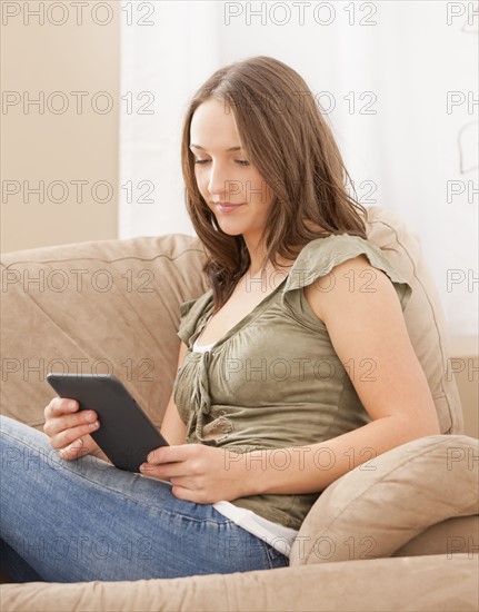 Young woman reading e-book on digital tablet. Photo : Mike Kemp