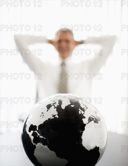 Globe with defocused businessman in background.