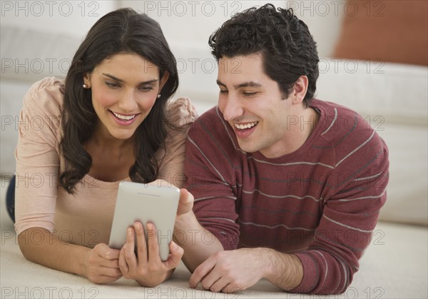 Couple lying on floor using palmtop.