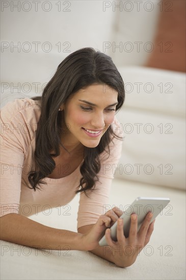 Woman lying on floor using palmtop.