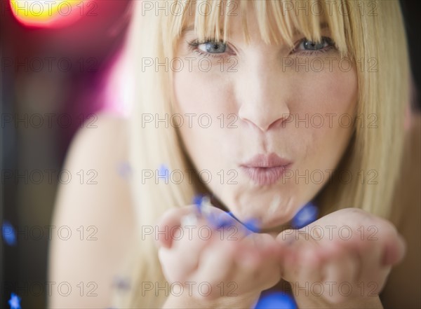 Young woman blowing confetti. Photo: Jamie Grill Photography