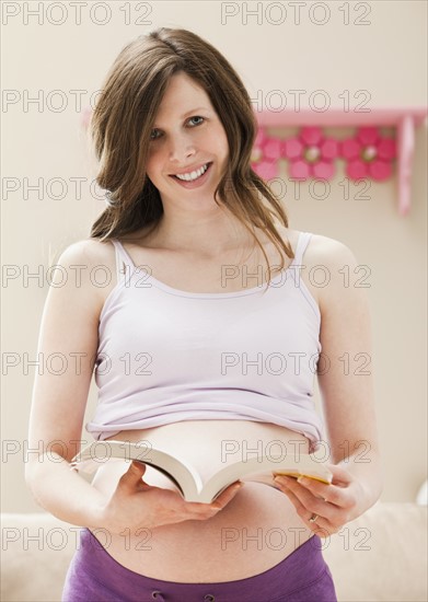 Young pregnant woman holding open book. Photo: Mike Kemp