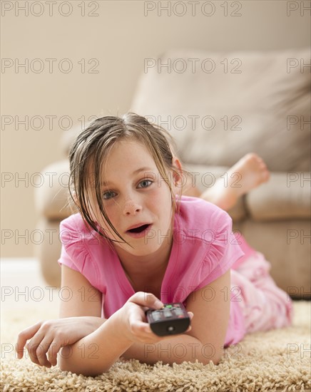 Portrait Of Girl 10 11 Lying On Floor Holding Remote Control Photo