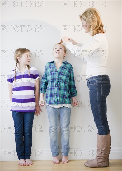 Mother measuring daughters' (8-11) height. Photo: Jamie Grill Photography