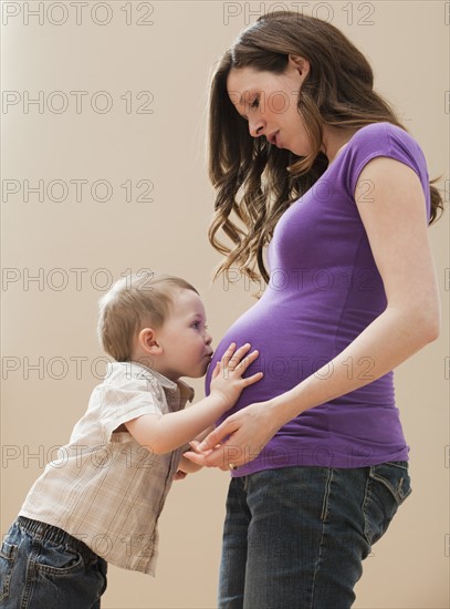 Portrait of boy (2-3) kissing pregnant mother's belly. Photo: Mike Kemp