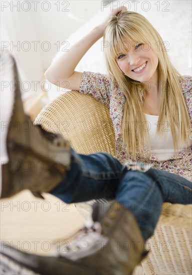 Young woman sitting in wicker chair. Photo: Jamie Grill Photography