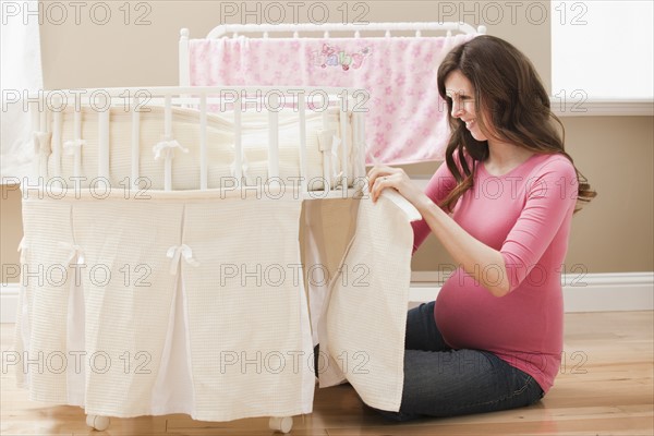 Young pregnant woman preparing playpen for new baby. Photo : Mike Kemp