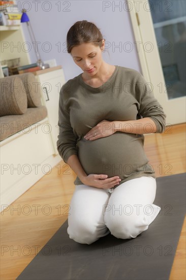 Expectant mother sitting on exercise mat. Photo : Rob Lewine