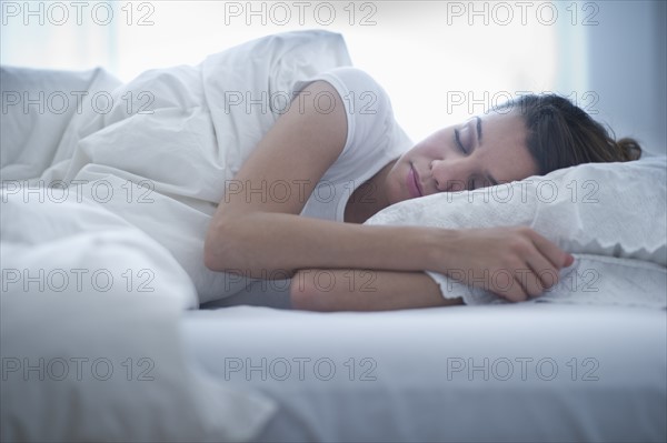 Happy young woman sleeping in bed.