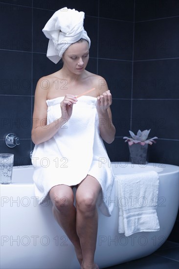 Mature woman sitting in bathroom wrapped in towel. Photo : Rob Lewine