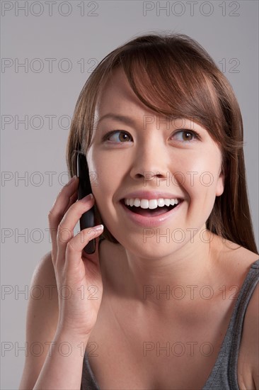 Portrait of young smiling woman using mobile phone, studio shot. Photo: Rob Lewine