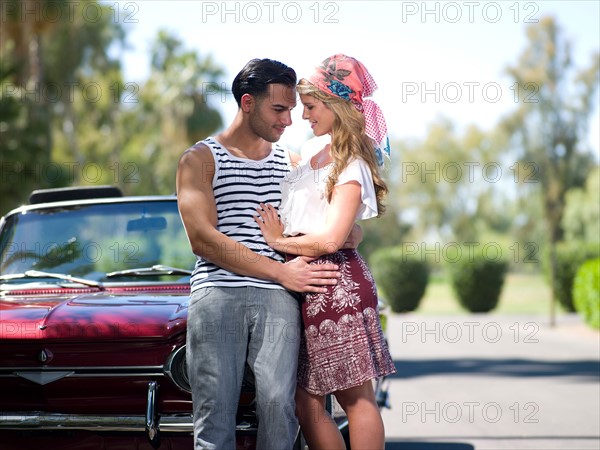 Couple embracing near convertible car. Photo: db2stock