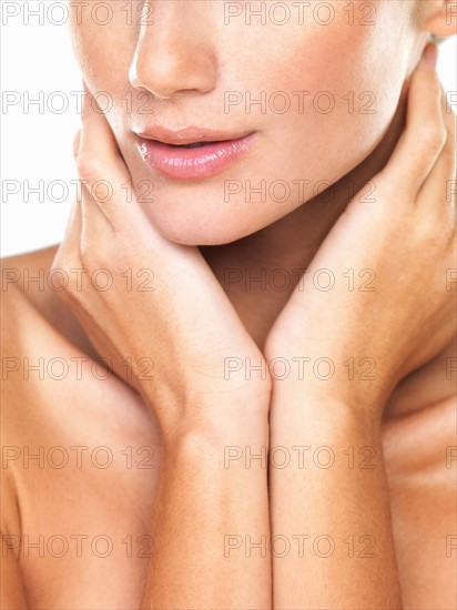 Studio portrait of beautiful woman with hands over neck. Photo: momentimages