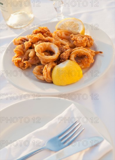 Greece, Cyclades Islands, Mykonos, Calamari appetizer on set table by sea.