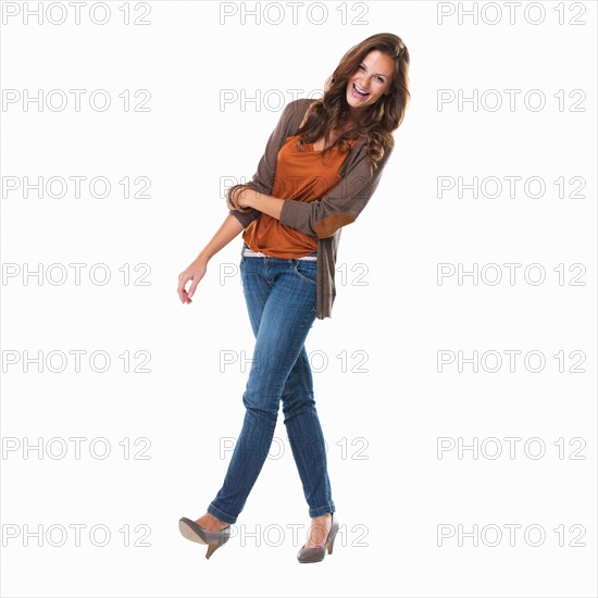 Studio shot of young woman smiling and walking. Photo: momentimages
