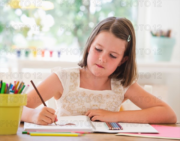 Close up of girl (6-7) drawing in notebook. Photo : Daniel Grill