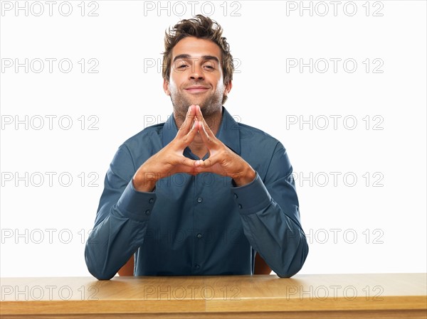 Smiling business man sitting at table and gesturing. Photo : momentimages