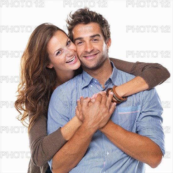 Studio shot of young couple smiling and embracing. Photo: momentimages