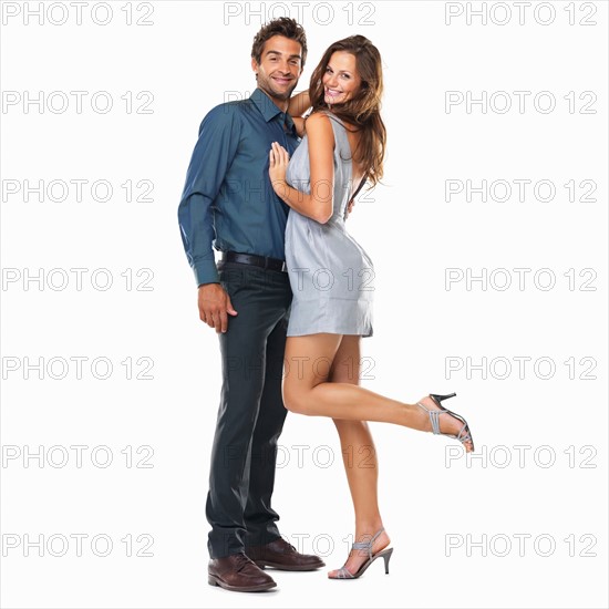 Studio shot of young couple standing together and smiling. Photo: momentimages