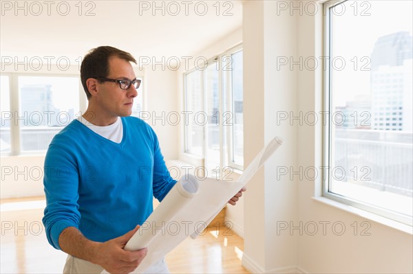 Architect reading blueprint in new office.