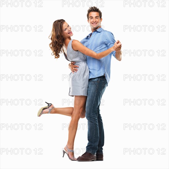Studio shot of young couple dancing together and smiling. Photo: momentimages