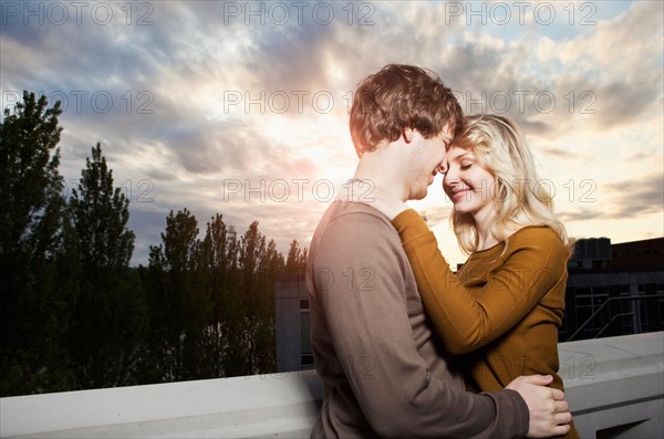 Young couple embracing under sunset sky. Photo: Take A Pix Media