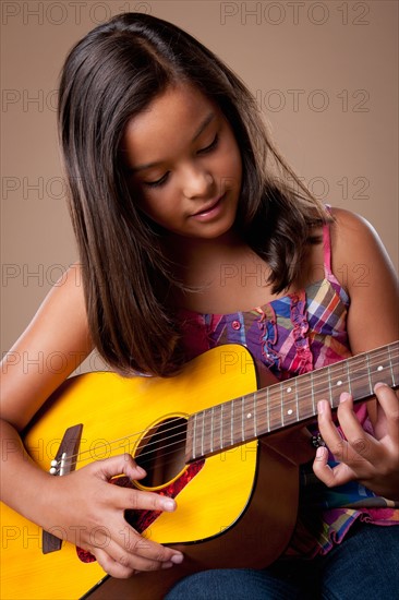Studio shot of girl (10-11) playing guitar. Photo: Rob Lewine