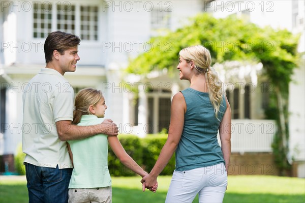 Parents with daughter (10-11) in front of house.